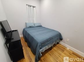 Brooklyn apartment for rent - A bedroom with a bed, a television, and a wooden floor.