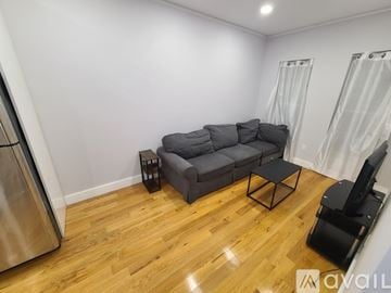 Brooklyn apartment for rent - A living room with a grey couch and a wooden floor.