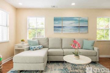 Key West condo for rent - A living room with a grey couch, a white coffee table, and a painting of a beach scene on the wall.