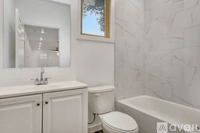 Tampa apartment for rent - A white bathroom with a marble wall and a toilet.