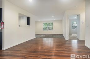 Kalamazoo apartment for rent - A spacious room with wooden floors and a window with a view of trees.