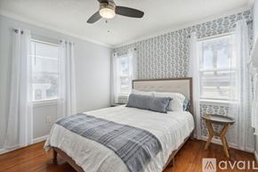 Fernandina Beach townhouse for rent - A bedroom with a bed, a ceiling fan, and a window with curtains.