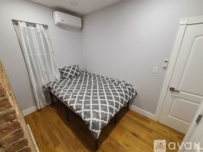 Brooklyn apartment for rent - A bedroom with a bed, wooden floor, and a white door.