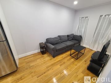 Brooklyn apartment for rent - A living room with a grey couch and a wooden floor.