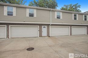 Kalamazoo townhouse for rent - A row of houses with garages and a tree in the background.