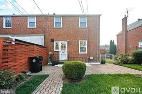 Towson house for rent - A brick house with a white door and a small garden in front.