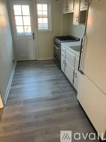 Towson house for rent - A kitchen with white appliances and wooden floors.