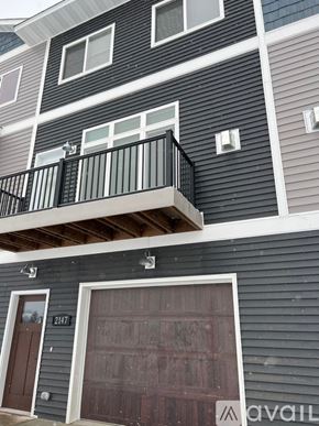 North Mankato apartment for rent - A two-story building with a balcony on the second floor and a garage door on the first floor.