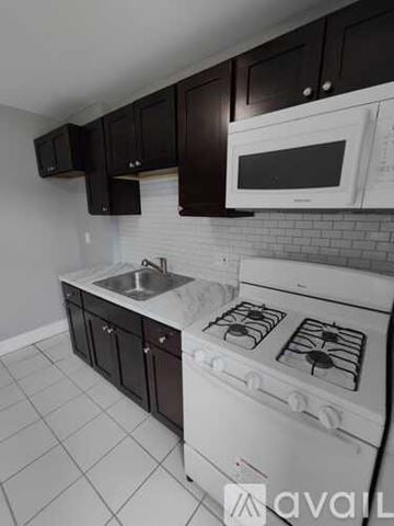 Blackwood apartment for rent - A kitchen with a white stove top oven and black cabinets.