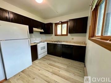 Fond Du Lac apartment for rent - A kitchen with a white fridge, black cabinets, and wooden floors.
