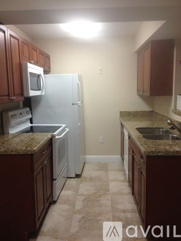 Miami apartment for rent - A kitchen with brown cabinets and a white refrigerator.