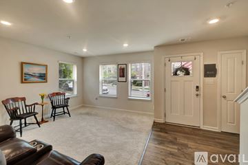 Baltimore house for rent - A living room with a brown leather couch, a painting, and a window with a view of the outside.