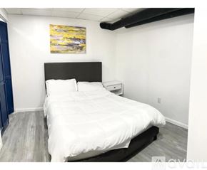 Cincinnati apartment for rent - A bedroom with a white bed and a painting on the wall.