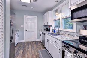 Hampton house for rent - A kitchen with white cabinets and a wooden floor.