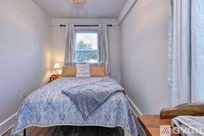 Hampton house for rent - A bedroom with a bed, a window with curtains, and a lamp on a nightstand.