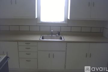 Taylor house for rent - A kitchen with white cabinets and a window above the sink.