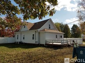 Terre Haute house for rent - A white house with a brown roof and a fence in front of it.