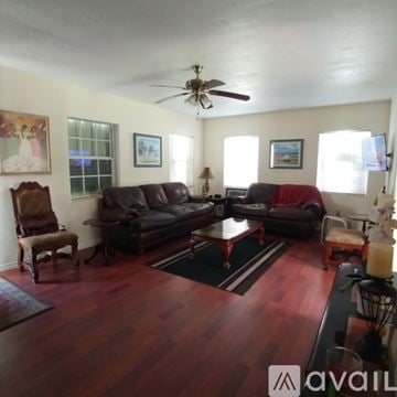 Coral Gables house for rent - A living room with a brown leather couch and a wooden floor.