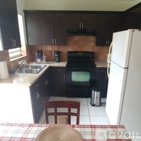 Coral Gables house for rent - A kitchen with black cabinets and a white fridge.