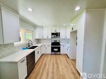 Palmdale house for rent - A kitchen with white cabinets and a wooden floor.