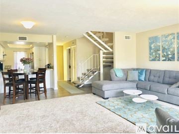 Carlsbad house for rent - A living room with a grey couch and a dining table with chairs.