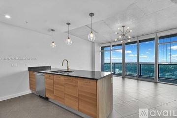 Miami condo for rent - A modern kitchen with wooden cabinets and a large window overlooking the city.