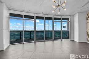 Miami condo for rent - A room with a large window overlooking a cityscape.