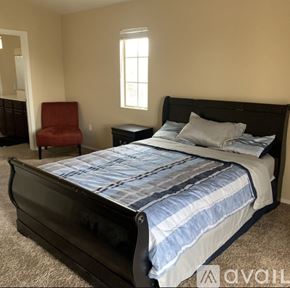 Goodyear townhouse for rent - A bedroom with a large bed and a red chair.