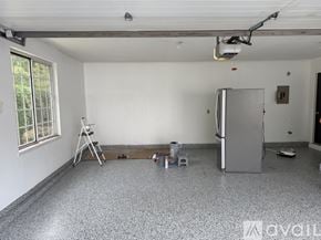Slinger apartment for rent - A room with a grey floor, white walls, and a window with a view of trees.