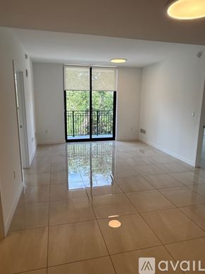 Miami apartment for rent - A spacious room with tiled flooring and a sliding glass door leading to a backyard.