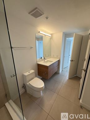Miami apartment for rent - A bathroom with a toilet, sink, and mirror.