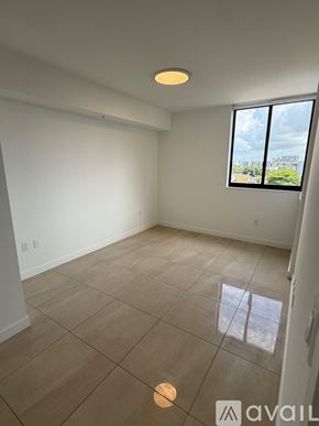 Miami apartment for rent - A room with a large window and tiled flooring.