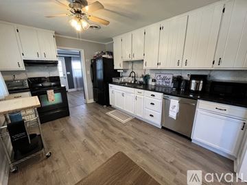 Newark house for rent - A kitchen with white cabinets and a black fridge.