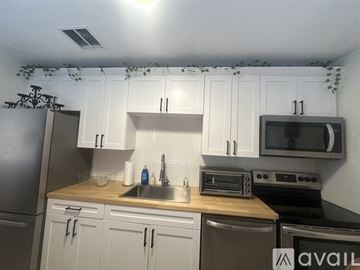 St. Petersburg house for rent - A kitchen with white cabinets and a stainless steel refrigerator.