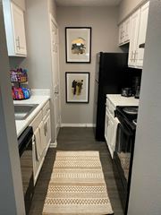 Dallas apartment for rent - A kitchen with a black fridge and white cabinets.