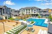 Austin apartment for rent - A large swimming pool surrounded by a fence and a patio area with chairs and a table.