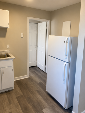 Dartmouth apartment for rent - A white refrigerator stands in a kitchen with a white cabinet and a white door.
