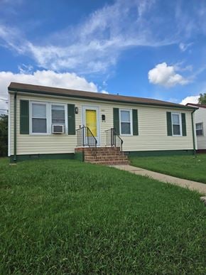 Richmond house for rent - A small house with a yellow door and green shutters.