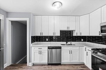 Hammond house for rent - A kitchen with white cabinets and black countertops.