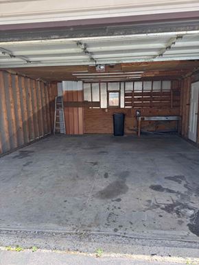 Findlay apartment for rent - A dirty garage with a trash can and a ladder.