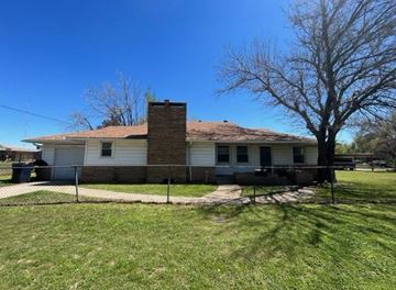 Oklahoma City house for rent - A house with a white siding and a brown roof is surrounded by a fence.