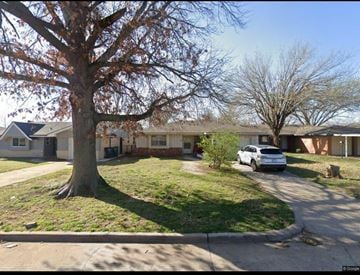 Oklahoma City house for rent - A tree with brown leaves stands in front of a house.