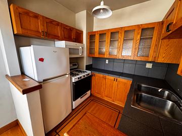 Alameda apartment for rent - A kitchen with wooden cabinets and a white refrigerator.