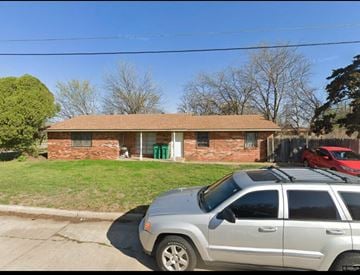 Oklahoma City house for rent - A silver car is parked in front of a brick house.