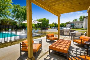 Huntsville apartment for rent - A wooden patio with orange cushions and a pool in the background.