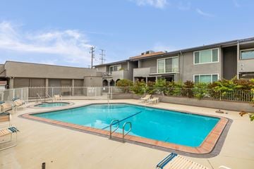 Downey apartment for rent - A swimming pool surrounded by a fence and chairs.