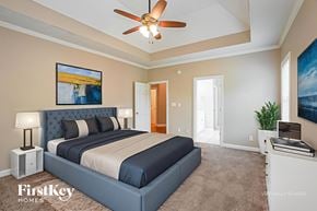 Clarksville house for rent - A bedroom with a large bed and a ceiling fan.