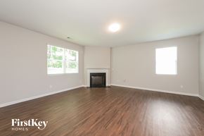 Gainesville house for rent - A spacious room with wooden floors and a fireplace.