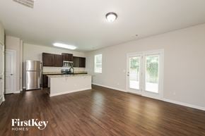 Gainesville house for rent - A spacious kitchen with wooden floors and a stainless steel refrigerator.