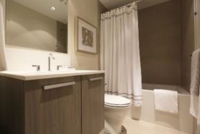 Vancouver apartment for rent - A white toilet sits in a bathroom next to a sink and a shower curtain.